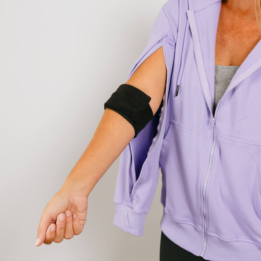 Woman wearing lavender zip hoodie with black arm wrap showing adaptive sleeve access design.