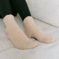 Person wearing beige rest day socks with dark green pants, close-up detail view.