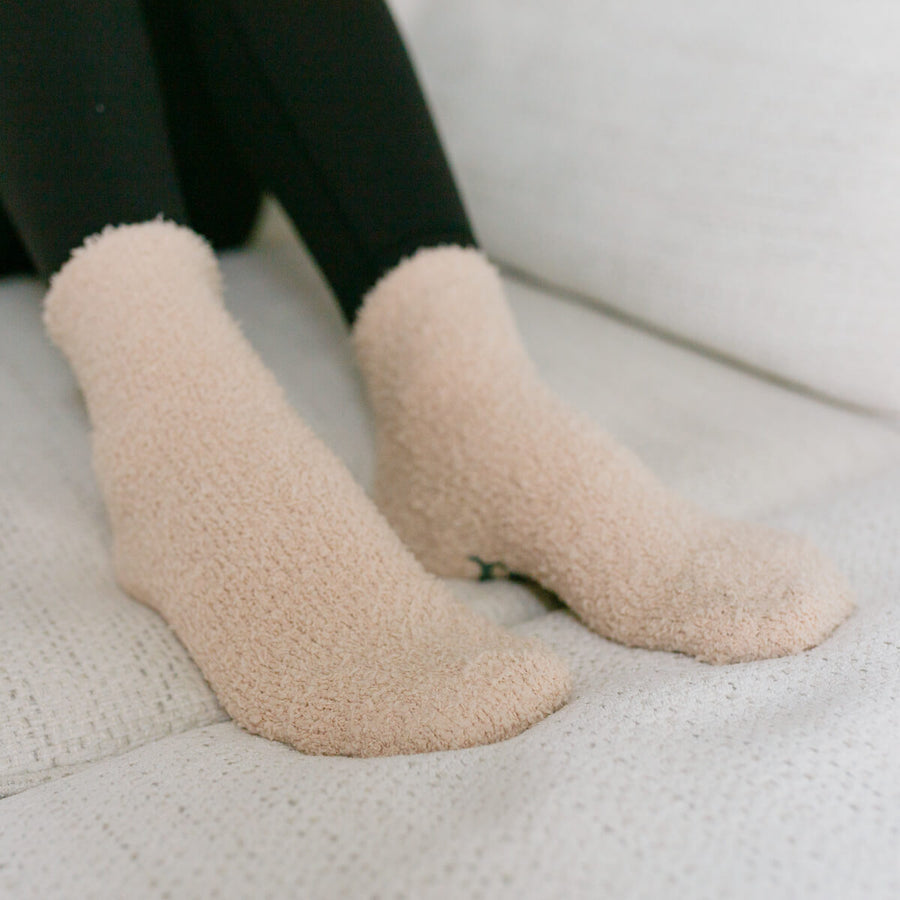 Person wearing beige rest day socks with dark green pants, close-up detail view.