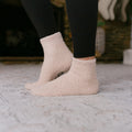 Person wearing cream-colored fuzzy Rest Day Socks, close-up lifestyle view on pavement.
