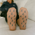 Close-up of tan cork Rest Day socks with teal awareness ribbon pattern on soles.