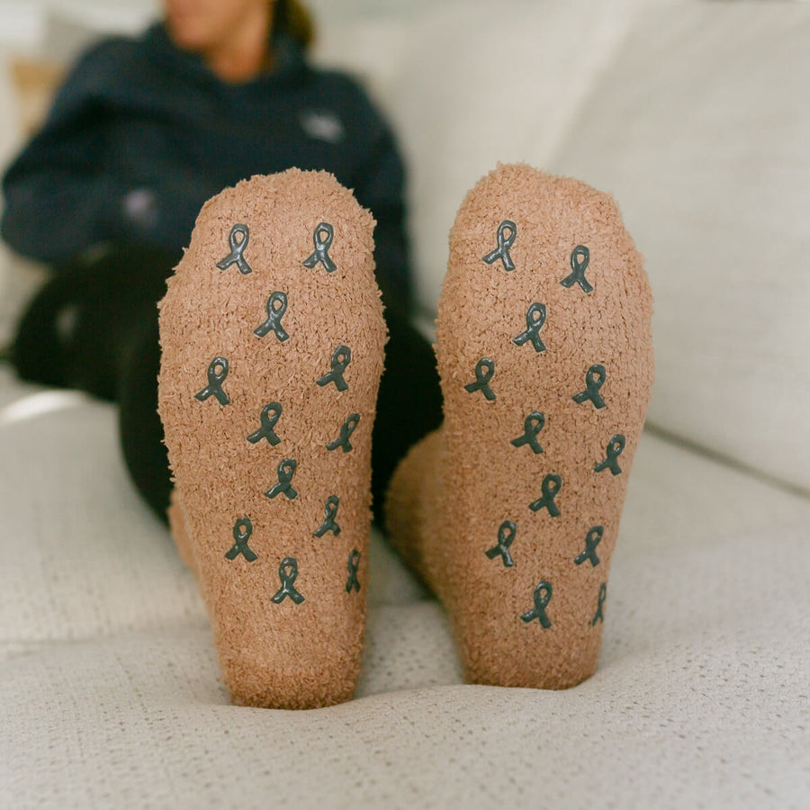 Close-up of tan cork Rest Day socks with teal awareness ribbon pattern on soles.