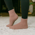 Person wearing mauve fuzzy Rest Day socks with dark tights, standing outdoors.
