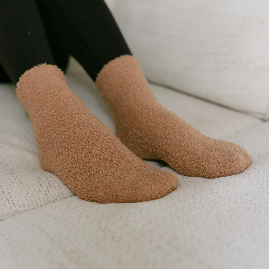 Person wearing tan rest day socks with textured fuzzy fabric, close-up detail view.