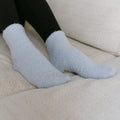 Person wearing light blue rest day socks while seated on beige couch.