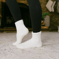 Person wearing white rest day socks with black leggings, standing on concrete ground.