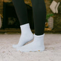 Person wearing white rest day socks with black leggings, standing outdoors on pavement.