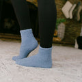 Person wearing light blue fuzzy Rest Day socks with black leggings, standing on concrete.