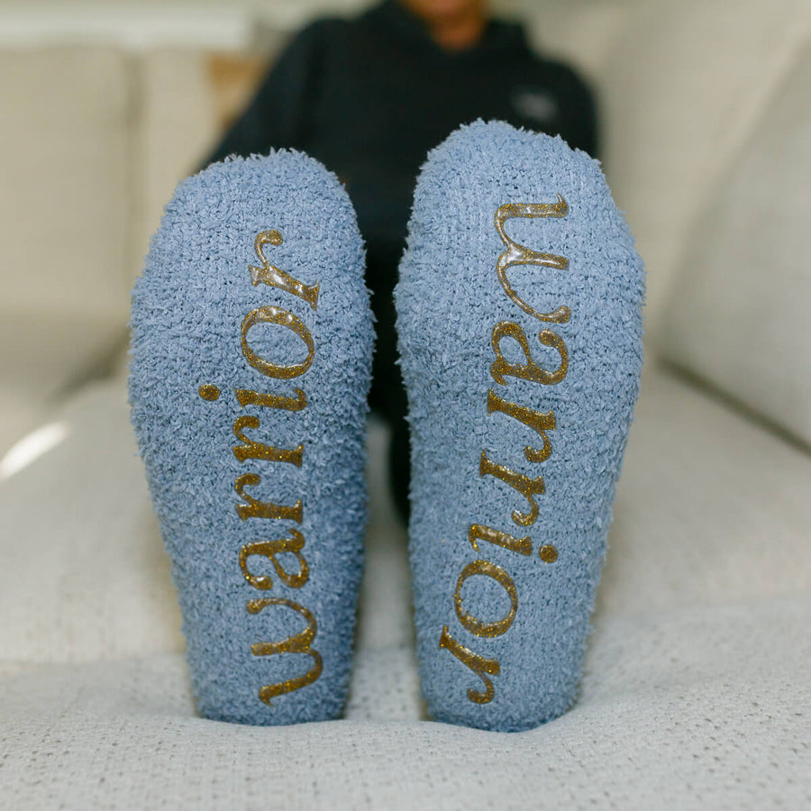 Close-up of light blue rest day socks with gold text on soles.