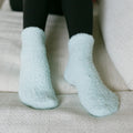 Person wearing light blue fuzzy rest day socks, close-up detail view.