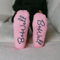 Close-up of pink Rest Day socks with "BeWell" text printed on soles.