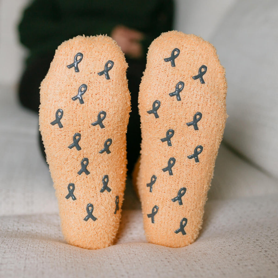 Close-up of tan rest day socks displaying dark blue awareness ribbon pattern on both soles.