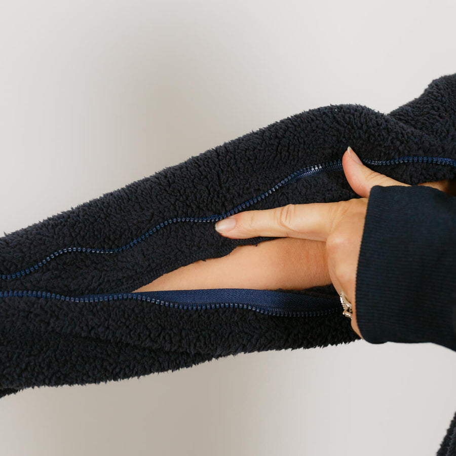 Close-up of black sherpa hoodie showing blue-lined zipper detail on arm access feature.
