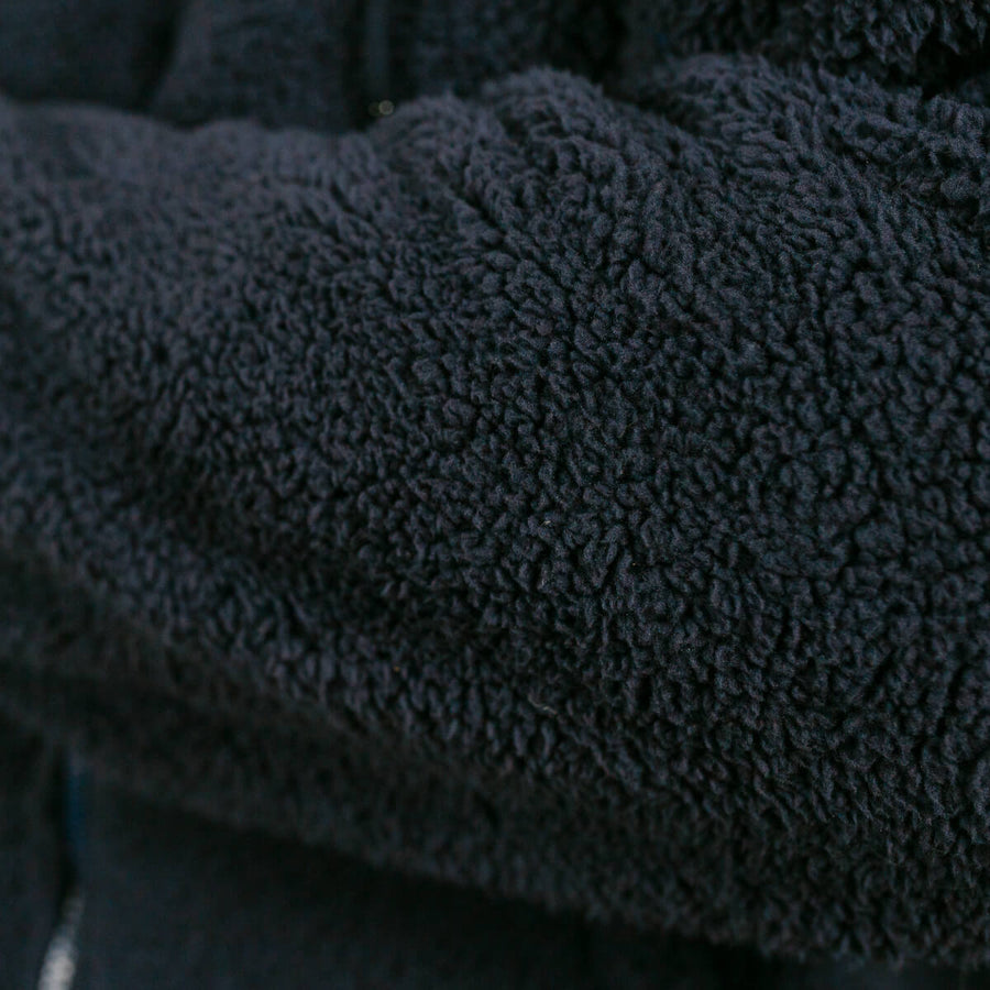 Close-up of dark gray sherpa hoodie fabric texture and weave detail.