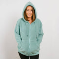 Woman wearing sage green sherpa zip hoodie with hood, front view.