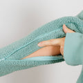 Close-up of sage green sherpa hoodie showing open side zipper and arm access detail.