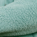 Close-up of sage green sherpa fabric texture on IV zip hoodie.