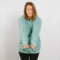 Woman wearing sage green sherpa zip hoodie with front zipper closure, front view.