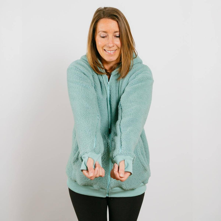 Woman wearing sage green sherpa zip hoodie with front zipper closure, front view.