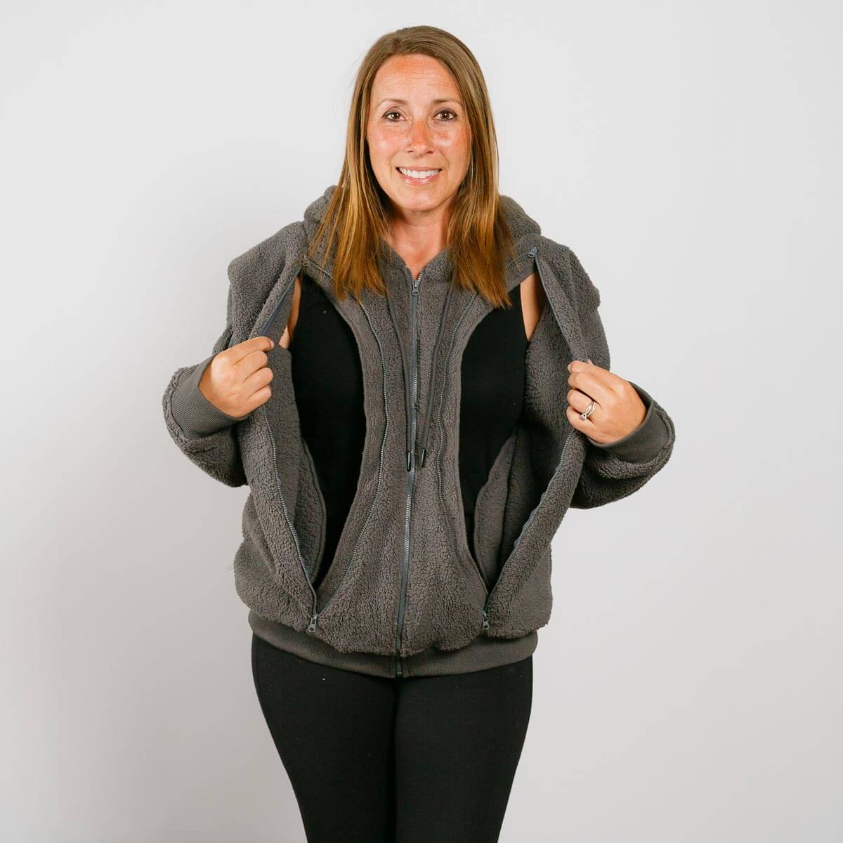 Woman wearing gray sherpa zip hoodie with black interior lining over black shirt, smiling at camera.