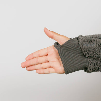 Child's hand extending from gray sherpa fleece sleeve with ribbed cuff against white background.