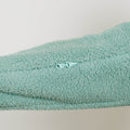 seafoam color sherpa fabric shows a white zipper pull detail against textured fleece material.