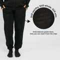 Black sweatpants with embroidered text on the back pocket that reads upside down when worn.