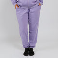 Person wearing lavender sweatpants with black socks against a white background. | Model is 5'3" 130lbs wearing size S