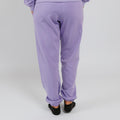 Person wearing lavender purple sweatpants with cuffed ankles, viewed from behind.