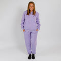 Woman wearing a lavender zip-up hoodie and matching sweatpants with black socks. | Model is 5'3" 130lbs wearing size S