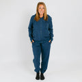 Woman wearing a navy blue zip-up hoodie and matching sweatpants with black socks. | Model is 5'3" 130lbs wearing size S