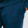 Dark blue sweatpants with embossed text on the thigh, worn by a person in a matching blue ribbed top.