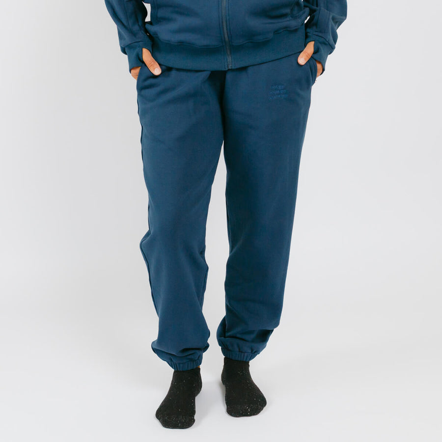 Person wearing teal blue jogger sweatpants with elastic cuffs and black socks.