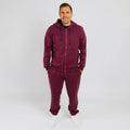 Man wearing burgundy zip-up hoodie and matching sweatpants standing against white background. | Model is 5'8" 165lbs wearing size M