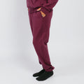 Person wearing maroon sweatpants with ripped knees, paired with black socks against a white background.