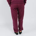 Person wearing maroon sweatpants viewed from behind, standing against white background.