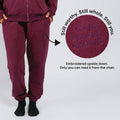 Maroon sweatpants with upside-down embroidered text on the thigh visible only when seated.