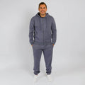 Man wearing a slate blue zip-up hoodie and matching gray sweatpants with white socks. | Model is 5'8" 165lbs wearing size M