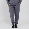 Person wearing gray sweatpants with orange thumb holes and black socks against white background. | Model is 5'3" 130lbs wearing size S