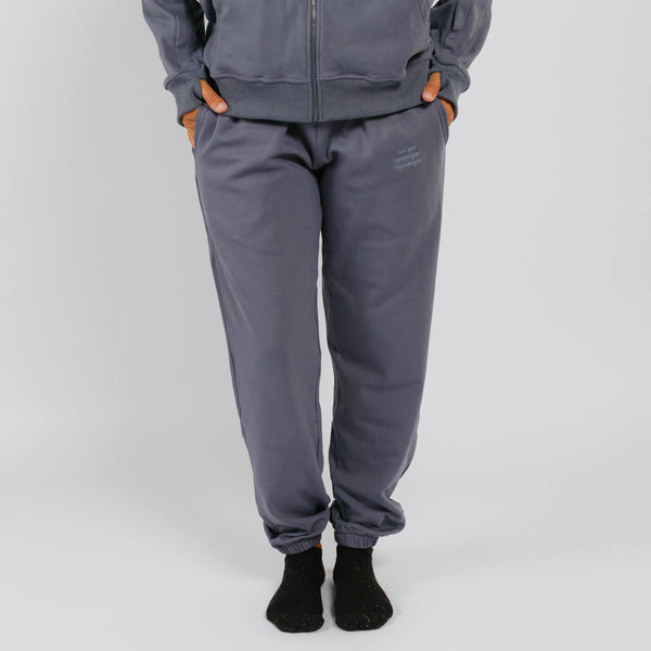 Person wearing gray sweatpants with orange thumb holes and black socks against white background. | Model is 5'3" 130lbs wearing size S