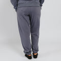 Person wearing slate blue sweatpants with cuffed ankles, viewed from behind against a white background.