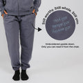 Slate blue sweatpants with upside-down embroidered text on the back pocket visible only when seated.