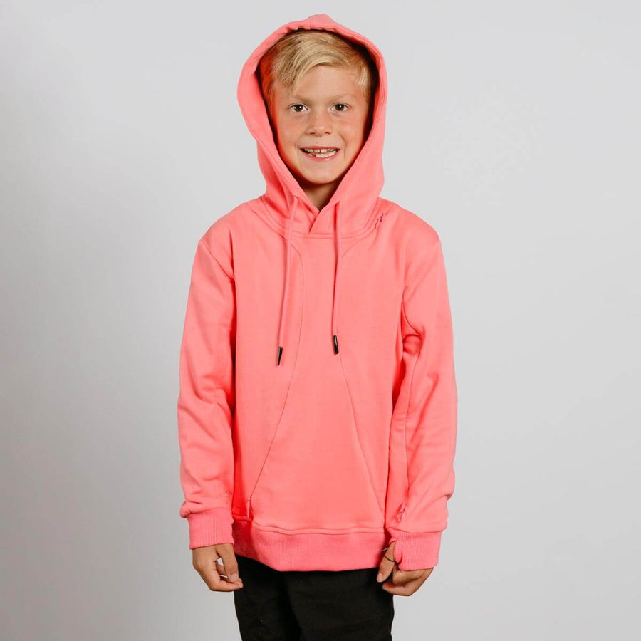 Young child wearing a bright pink hoodie with drawstrings and black pants, smiling at camera.