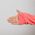 Child's hand extended from coral-pink ribbed sleeve cuff against neutral background.