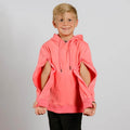 Young child wearing a coral pink hoodie with cutout sleeves and black pants, smiling at camera.